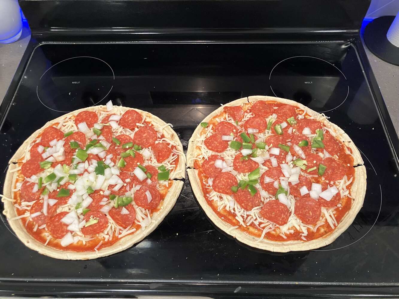 Homemade pizza with chicken, pepperoni, jalapeños and onions ready to go in the oven